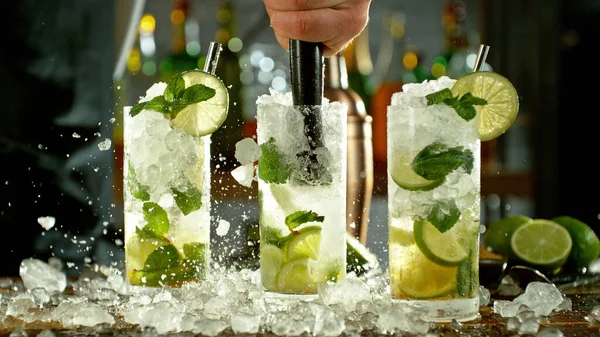 Preparation of mojito drinks on bar counter. Fresh beverages background.