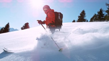 Free ride skier running down the hill. Powder snow is flying up in the air.