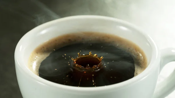 Detail of coffee drop falling into cup of coffee. Macro shot of black hot coffee drink.