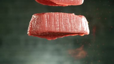 Masaya düşen uçan çiğ biftek parçaları. Kamera hızlı çekimde. Yüksek hızlı sinema kamerası Phantom VEO 4k, 1000 fps. Yüksek hızlı sinüs robotuna yerleştirilmiş. Önplanda ateş.