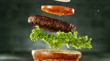 Hamburger parçalarını istiflemek için süper yavaş çekim. Kamera hareket halinde. Yüksek hızlı sinema kamerası, 1000 fps. Yüksek hızlı sinüs robotuna yerleştirilmiş. Arkaplanda ateş.