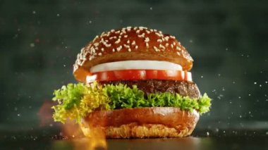 Hamburger parçalarını istiflemek için süper yavaş çekim. Kamera hareket halinde. Yüksek hızlı sinema kamerası, 1000 fps. Yüksek hızlı sinüs robotuna yerleştirilmiş. Arka planda yangın. Hız rampası etkisi.