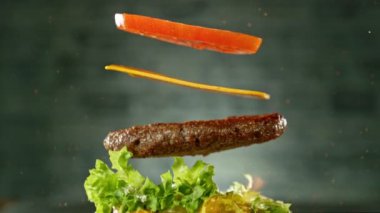 Çizburger parçalarını istiflemek için süper yavaş çekim. Kamera hareket halinde. Yüksek hızlı sinema kamerası, 1000 fps. Yüksek hızlı sinüs robotuna yerleştirilmiş. Arkaplanda ateş.