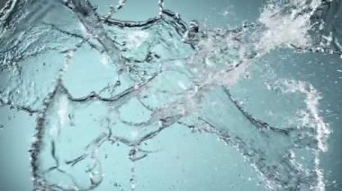 Mavi arka planda izole edilmiş çok yavaş su sıçratma hareketi. Yüksek hızlı sinema kamerası, 1000 fps..