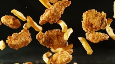 Patates kızartması ve kızarmış tavuk parçaları süper yavaş çekimde. Yüksek hızlı sinema kamerasında çekildi, 1000fps, yüksek hızlı sinüs robotuna yerleştirildi. Kamera hareket halinde, takip eden nesneler.