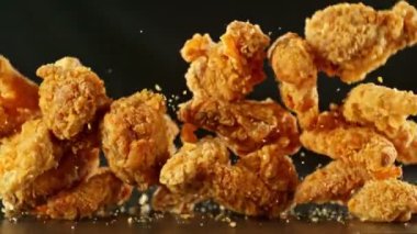 Siyah arka planda uçan kızarmış tavuk parçaları. Yüksek hızlı sinema kamerasında çekildi, 1000fps, yüksek hızlı sinüs robotuna yerleştirildi. Kamera hareket halinde, takip eden nesneler. Hız rampası etkisi.