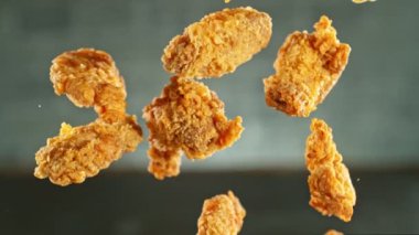 Gri arka planda uçan kızarmış tavuk parçaları çok yavaş hareket ediyor. Yüksek hızlı sinema kamerasında çekildi, 1000fps, yüksek hızlı sinüs robotuna yerleştirildi. Kamera hareket halinde, takip eden nesneler.