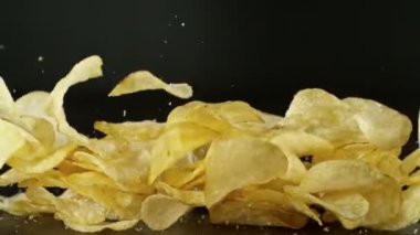 Siyah arka planda uçan kızarmış patates cipslerinin süper yavaş çekimi. Yüksek hızlı sinema kamerası, 1000 fps. Kamera yüksek hızlı sinüs robotuna yerleştirilmiş, hedefi takip ediyor. Hız rampası etkisi.