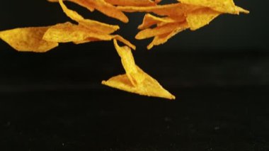Siyah arka planda uçan kızarmış tortilla cipsleri. Yüksek hızlı sinema kamerası, 1000 fps. Kamera yüksek hızlı sinüs robotuna yerleştirildi, hedefi takip ediyor..