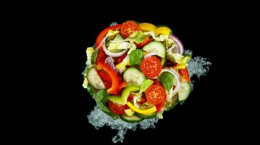 Siyah arka planda izole edilmiş, su sıçratan Yunan salatasının süper yavaş çekimi. Yüksek hızlı sinema kamerası, üst çekim. 