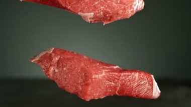 Masaya düşen uçan çiğ biftek parçaları. Yüksek hızlı sinema kamerası, 1000 fps. Yüksek hızlı sinüs robotuna yerleştirilmiş, kamera nesneyi izliyor. Hız rampası etkisi.