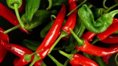 Siyah arka planda izole edilmiş kırmızı biberlerin dönüşümlü süper yavaş çekimi. Yüksek hızlı sinema kamerası, 1000 fps..