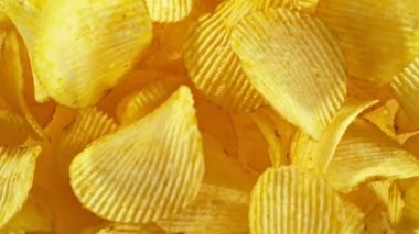 Sarı arka planda uçan kızarmış patates cipsleri süper yavaş çekimde. Yüksek hızlı sinema kamerası, 1000 fps. Kamera yüksek hızlı sinüs robotuna yerleştirildi, hedefi takip ediyor..