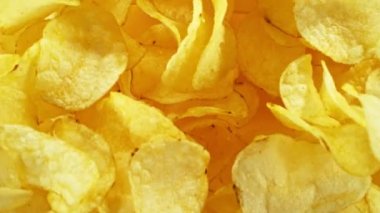 Sarı arka planda uçan kızarmış patates cipsleri süper yavaş çekimde. Yüksek hızlı sinema kamerası, 1000 fps. Kamera yüksek hızlı sinüs robotuna yerleştirildi, hedefi takip ediyor..