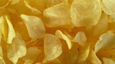 Sarı arka planda uçan kızarmış patates cipsleri süper yavaş çekimde. Yüksek hızlı sinema kamerası, 1000 fps. Kamera yüksek hızlı sinüs robotuna yerleştirildi, hedefi takip ediyor..