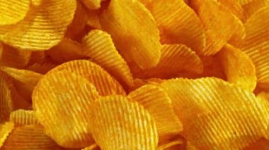 Sarı arka planda uçan kızarmış patates cipsleri süper yavaş çekimde. Yüksek hızlı sinema kamerası, 1000 fps. Kamera yüksek hızlı sinüs robotuna yerleştirildi, hedefi takip ediyor..