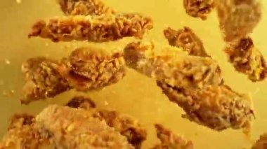 Sarı zemin üzerinde kızarmış tavuk parçaları uçuşan süper yavaş çekim. Yüksek hızlı sinema kamerası, 1000 fps. Kamera yüksek hızlı sinüs robotuna yerleştirilmiş, hedefi takip ediyor. Hız rampası etkisi.