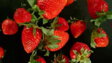 Siyah arka planda dönen çileklerin süper yavaş çekimi, üst manzara. Yüksek hızlı sinema kamerası, 1000 fps, yüksek hızlı sinüs robotuna yerleştirilmiş. Hız rampası etkisi.