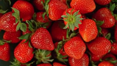 Siyah arka planda dönen çileklerin süper yavaş çekimi, üst manzara. Yüksek hızlı sinema kamerası, 1000 fps, yüksek hızlı sinüs botuna yerleştirilmiş..