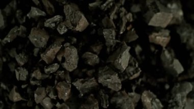 Siyah arka planda dönen kömür parçalarının süper yavaş çekimi. Yüksek hızlı sinema kamerası, 1000 fps, yüksek hızlı sinüs botuna yerleştirilmiş, hedefi takip ediyor..