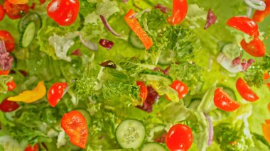Taze bahçe salatası havada uçuşuyor. Yeşil arka planda soyut lezzetli Yunan salatası.