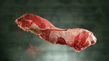 Uçan çiğ biftek parçası masaya düşüyor. Kamera hızlı çekimde. Yüksek hızlı sinema kamerası, 1000 fps. Yüksek hızlı sinüs robotuna yerleştirilmiş. Önplanda ateş.