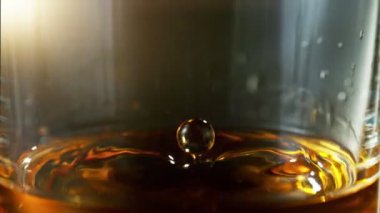 Viskiyi hızlı çekimle bardağa düşürmenin süper yavaş çekimi. Yüksek hızlı sinema kamerası, 1000 fps, yüksek hızlı sinüs robotuna yerleştirilmiş. Hız rampası etkisi.