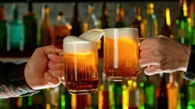 Bira bardaklarına vurmanın süper yavaş çekimi. Şerefe konsepti. Yüksek hızlı sinema kamerası, 1000 fps. Arka planda şişe olan bir bar. Hız rampası etkisi.