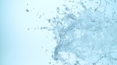 Yan taraftan su sıçrayan süper yavaş çekim, mavi arka planda izole edilmiş. Yüksek hızlı sinema kamerasıyla çekilmiş., 