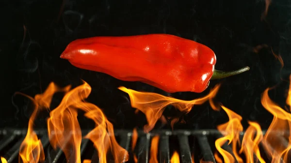 烧烤烤柳条掉落红辣椒 黑色背景下的烧烤火网 — 图库照片
