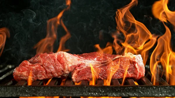 生牛ステーキでバーベキューグリル 黒の背景にバーベキュー火災グリッド — ストック写真