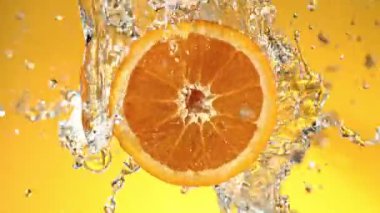 Super Slow Motion of Orange Slice With Water Splashes. Rotating Slice of Orange with Splashing Water Around. Isolated on Colored Background. Filmed on High Speed Cinema Camera, 1000 Fps. Speed Ramp.