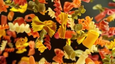 Siyah arka planda pişirilmemiş İtalyan makarnası karışımının süper yavaş çekimi. Yüksek hızlı sinema kamerası, 1000 fps, yüksek hızlı sinüs robotuna yerleştirilmiş, nesneyi takip ediyor. Hız rampası etkisi.