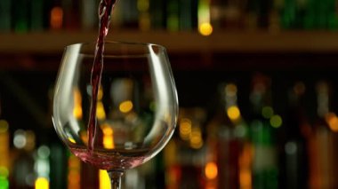 Super slow motion of pouring red wine into goblet. Bar with bottles on background. Filmed on high speed cinema camera, 1000fps.