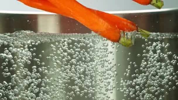 落下するニンジンの超スローモーション沸騰水に ステンレス鍋の中の野菜スープの概念 1000 Fpsの高速シネマカメラで撮影 — ストック動画