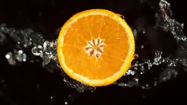 带有水花的橙片的超级慢动作 用溅水的橙子片旋转 被黑色背景隔离了 在高速电影摄影机上拍摄 1000 Fps 速度计 — 图库视频影像