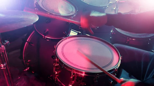 stock image Drummer Playing on Drums Assembly. Dramatic Scene with Colored Neon Lights. Concert and Performance Theme.