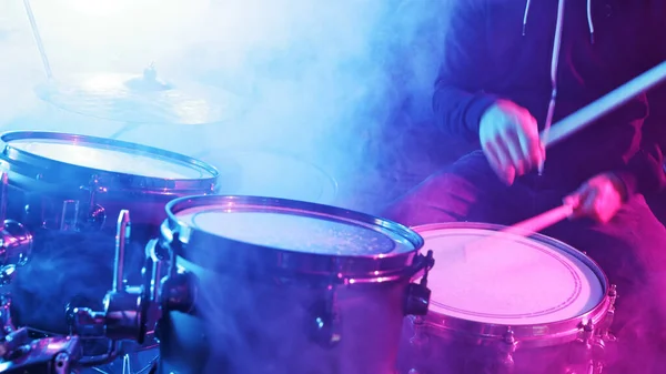 Drummer Playing on Drums Assembly. Dramatic Scene with Colored Neon Lights. Concert and Performance Theme.