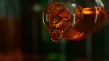 Şişeden Viski Doldurmanın Süper Yavaş Hareketi. Yüksek Hız Sinema Kamerası, 1000 Fps, Yüksek Hız Cine Bot 'a Yerleştirilmiş. Kamera Sıvı Akımı Takip Ediyor. Arkaplanda Şişeler Olan Bar.
