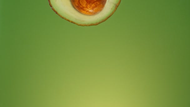 Super Zeitlupe Fallender Avocadofrüchte Ins Wasser Spritzen Auf Farbigem Hintergrund — Stockvideo