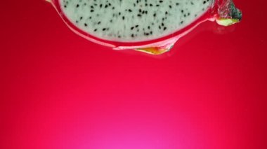 Süper Yavaş Düşen Dilimlenmiş Ejder Meyvesi veya Pitahaya (Pitaya). Renkli Arkaplanda Suya Atlama. Yüksek Hız Sinema Kamerası, 1000 fp..