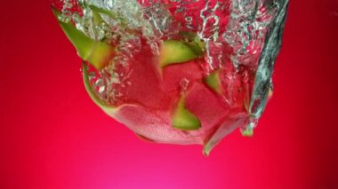 Düşen Ejder Meyvesinin Süper Yavaş Hareketi (Pitaya). Renkli Arkaplanda Suya Atlama. High Speed Cinema Camera 'da çekildi, 1000 fps. Hız Rampası Efekti.