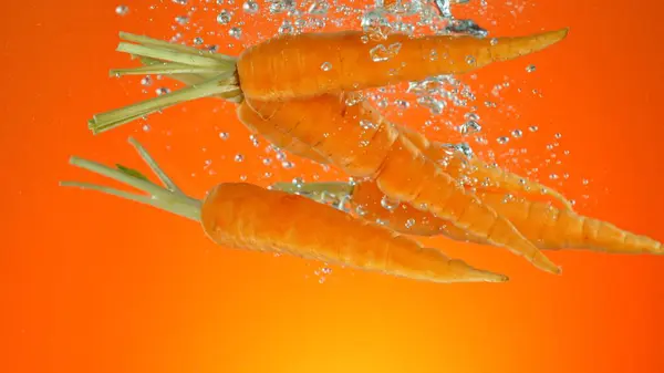 鲜活生鲜胡萝卜在水下冷冻运动 在彩色背景下分离 — 图库照片