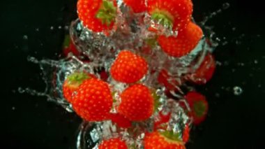Siyah arka plan üzerinde suya düşen çilek Süper yavaş hareket. Yüksek hızlı sinema kamera, 1000 fps filme.