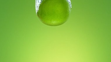 Yeşil arka planda izole edilmiş, suya düşen limonatanın süper yavaş hareketi. Yüksek Hız Sinema Kamerası, 1000 fp..