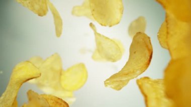 Parlak Arkaplanda Uçan Patates cipslerinin Süper Yavaş Hareketi. High Speed Cinema Camera 'da çekildi, 1000 fps. Kamera Yüksek Hız Cine Bot 'una yerleştirildi, Döndürülüyor.