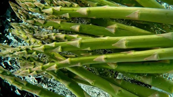 Bunch Fresh Asparagus Dropped Water Air Bubbles Splashes Isolated Black — Stock Photo, Image