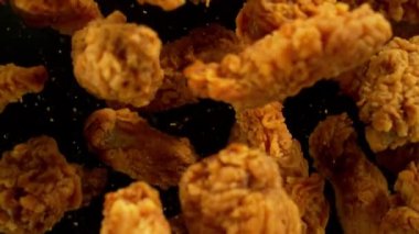 Siyah arka planda uçan kızarmış tavuk parçaları. Yüksek hızlı sinema kamerası, 1000 fps. Kamera yüksek hızlı sinüs robotuna yerleştirildi, hedefi takip ediyor..