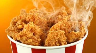 Kağıt kovada kızarmış tavuk parçaları, renkli arka planda izole edilmiş. Hurda Gıda Konsepti.