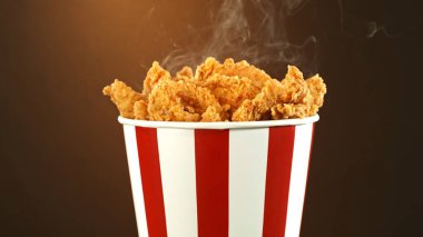 Kağıt kovada kızarmış tavuk parçaları, renkli arka planda izole edilmiş. Hurda Gıda Konsepti.